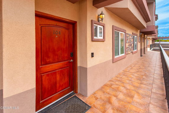 View of an exterior apartment hallway with door 104 and windows.