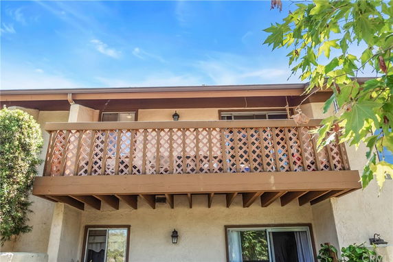 Front view of a two-story house with a balcony featuring lattice railing.