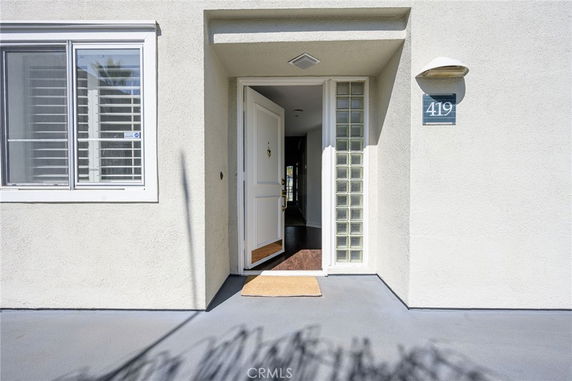 Front entrance of a house with an open door and a wall light fixture.