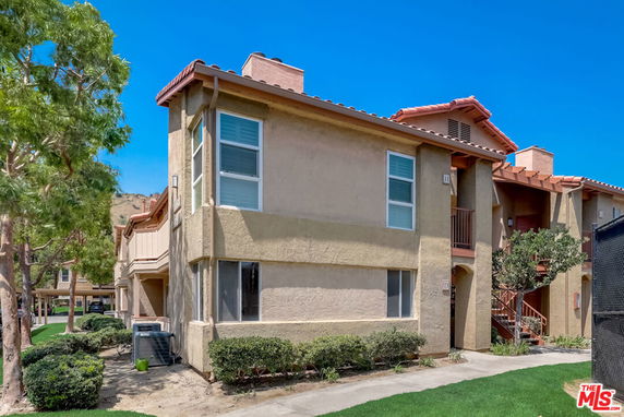Front view of a two-story apartment building with beige walls and red roof.