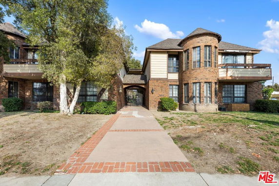 Front view of a two-story house with brick exterior and a central walkway.