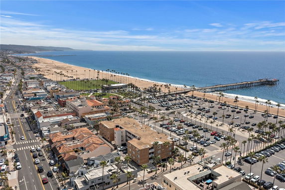 Wide view of a coastal cityscape with a pier, beach, and surrounding buildings.