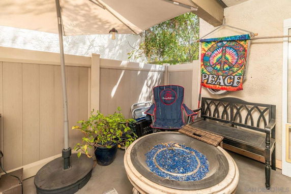 Small outdoor patio area with a fire pit, chairs, and decorative peace sign.