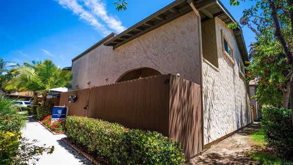 Front view of a two-story building with textured walls and a wooden fence.