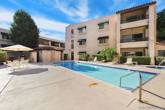 Outdoor swimming pool area with surrounding buildings and lounge chairs.
