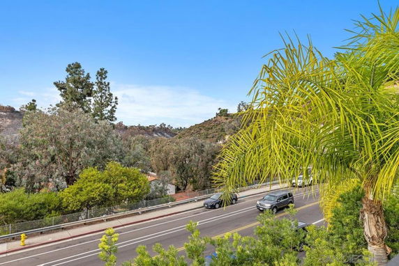 View of a road surrounded by trees and hills in the background.