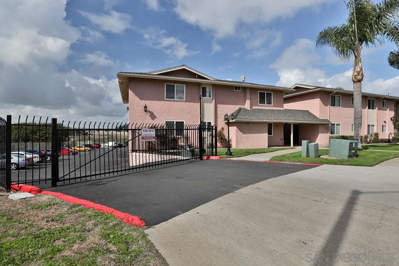 Front view of a two-story residential building with a gated entrance.