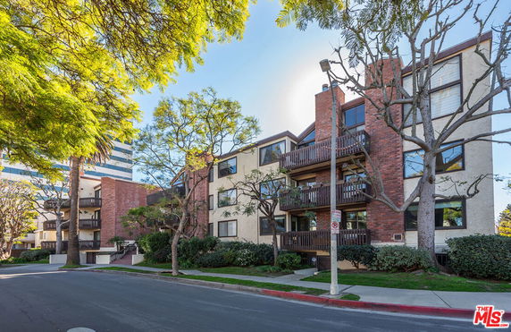 Front view of a multi-story apartment building with balconies and red brick facade.
