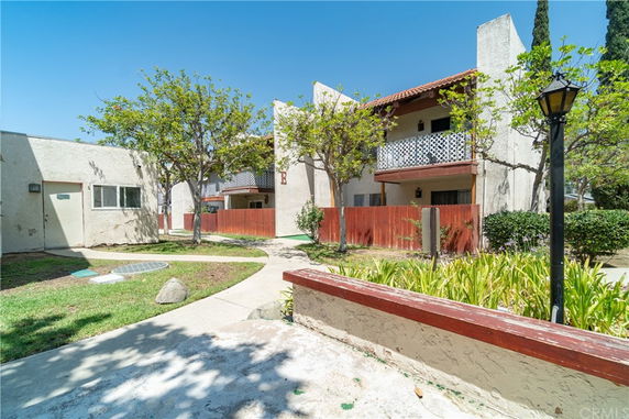 Front view of a building with balconies and a red fence.