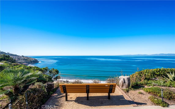 Wide view of the ocean from a cliffside with a bench.