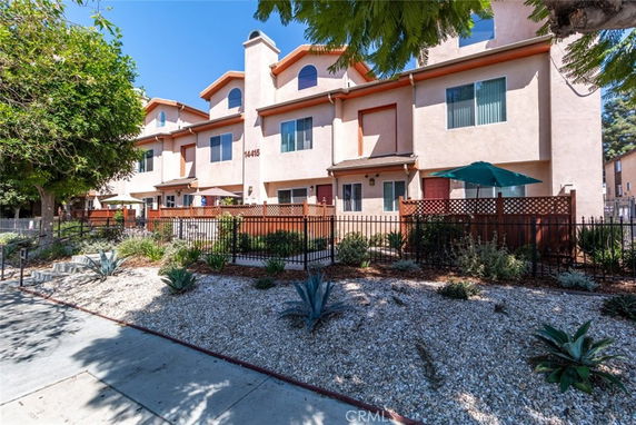 Front view of a multi-story residential building with a fenced garden area.