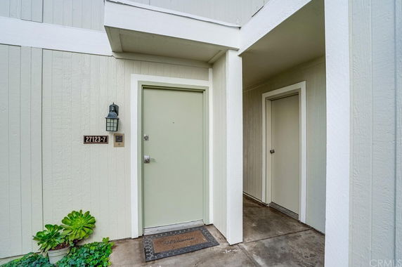 Front view of a house entrance with a light green door and outdoor light fixture.