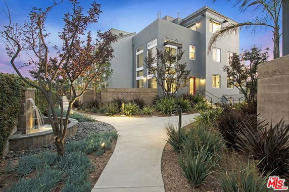 Front view of a contemporary multi-story building with landscaped pathway and modern architecture.