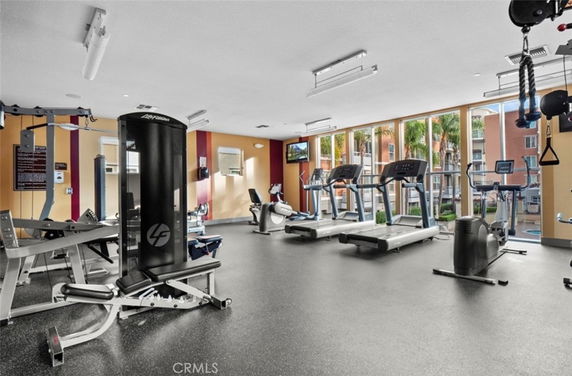 Interior view of a gym with fitness equipment and large windows.