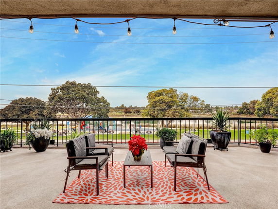 Outdoor seating area with a view of a park and trees in the background.