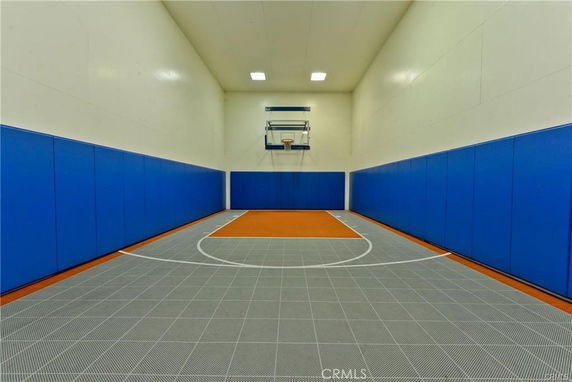 Indoor basketball court with blue wall padding and a hoop.