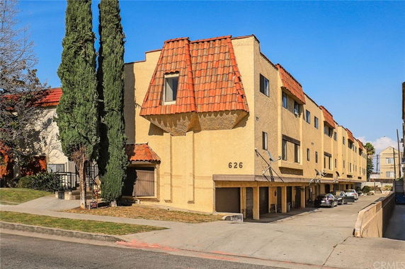 Front view of a multi-story building with a unique roof design and parking area beneath.