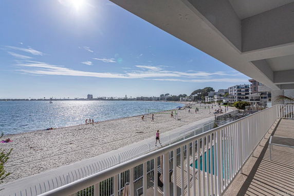 Panoramic beach view from a building balcony overlooking the ocean and shoreline.