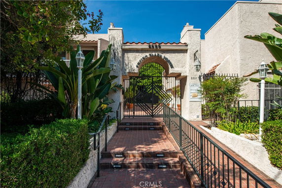 Front view of a building entrance with an arch and gated pathway.