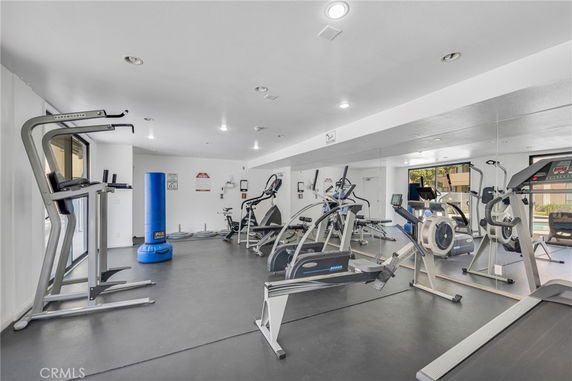 Indoor gym with exercise equipment and floor-to-ceiling mirrors.