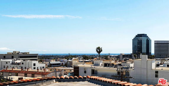 Panoramic view of a cityscape with buildings and a distant ocean view.