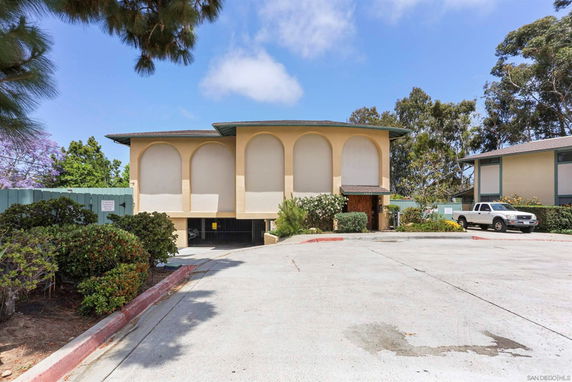 Front view of a two-story building with arched window designs and a driveway leading to a parking area.