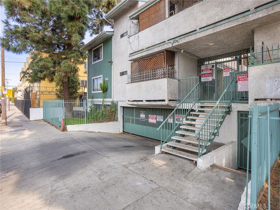 Front view of a multi-story residential building with stairs and fencing.