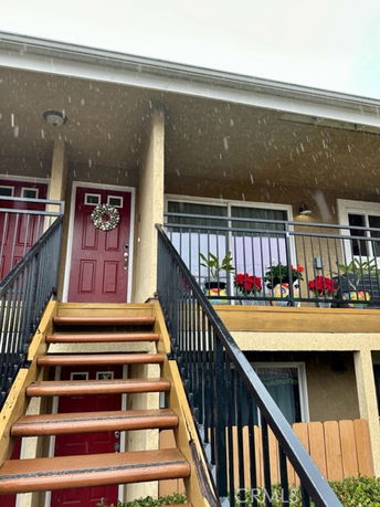 Front view of a two-story building with a red door and exterior staircase.