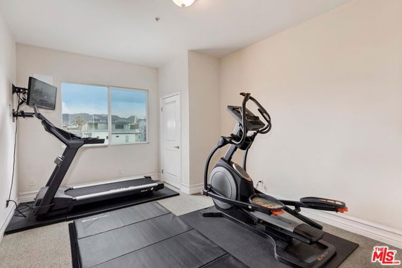 Room with exercise equipment including a treadmill and elliptical machine.