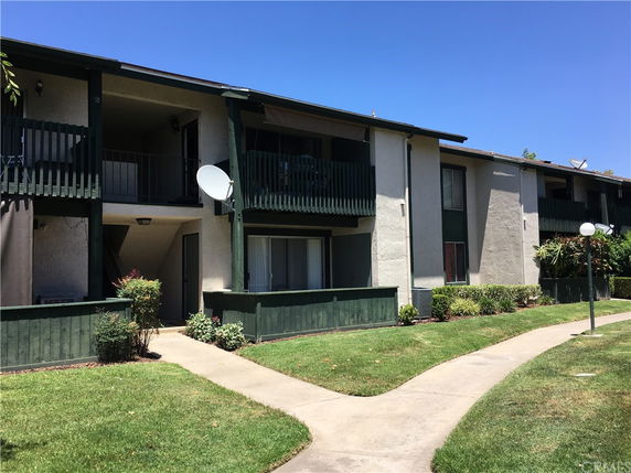 Front view of a two-story apartment building with balconies and a walkway.