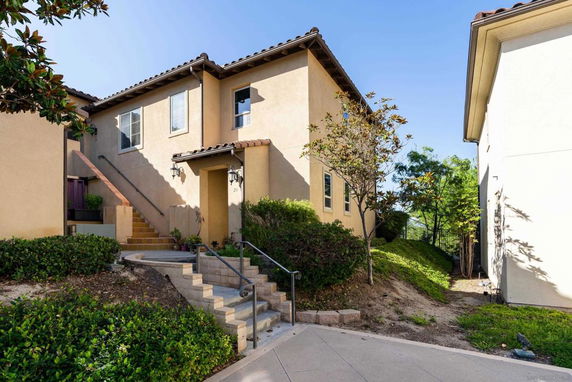 Front view of a two-story house with stairs leading to upper entrance.