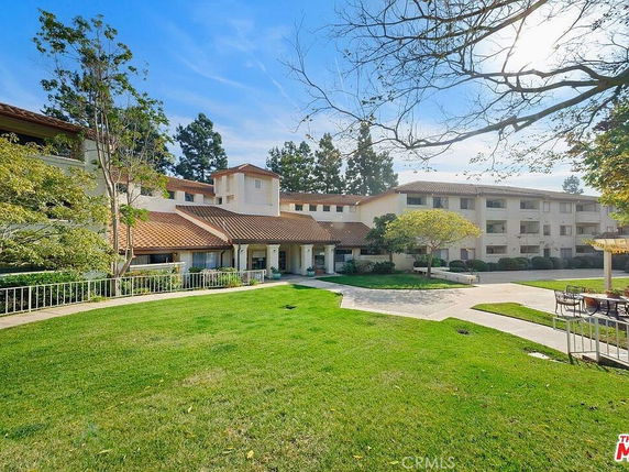 Front view of a multi-story residential building with a central entrance and surrounding greenery.