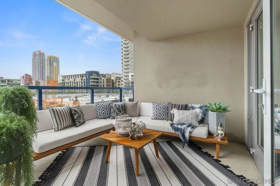 Outdoor seating area on a balcony with a view of surrounding buildings.