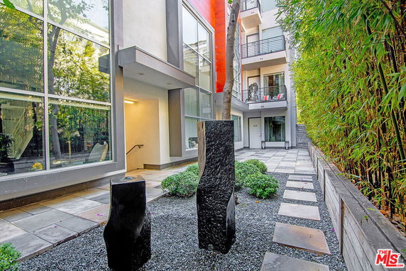 Front view of a modern multi-story building with large glass windows and a pathway.