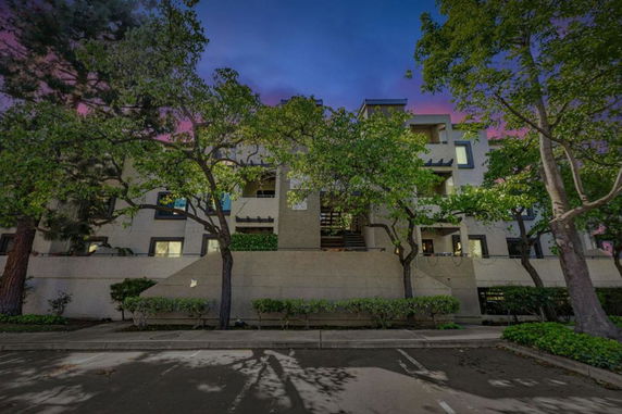 Front view of a multi-story residential building with surrounding trees.