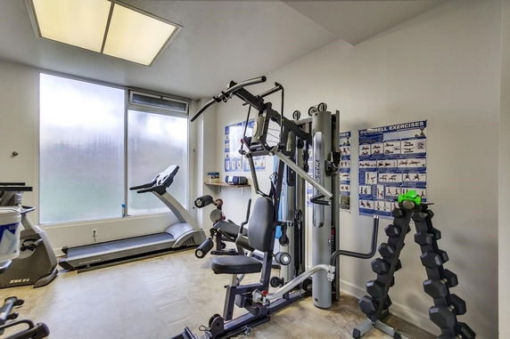 Indoor gym area with exercise equipment including a treadmill and weight machine.