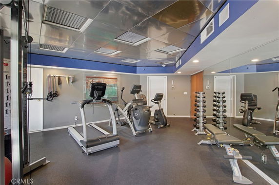 Indoor gym with exercise equipment including treadmills, stationary bikes, and dumbbells.