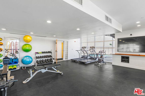 Fitness area with gym equipment including treadmills and dumbbells.