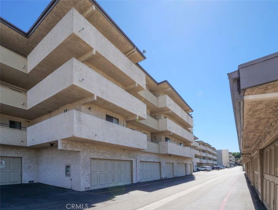 Front view of a multi-story apartment building with balconies and garages.