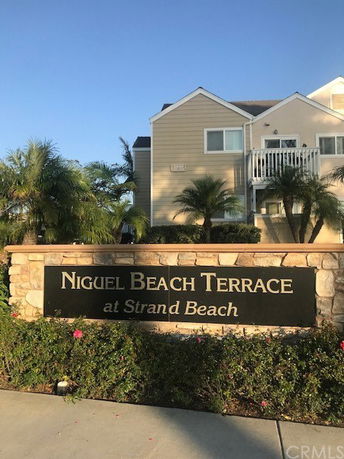 Front view of a residential building with a sign reading Niguel Beach Terrace at Strand Beach.