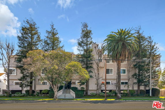 Front view of a multi-story residential building with trees in front.