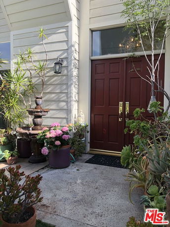 Front view of a house entrance with red double doors and potted plants.