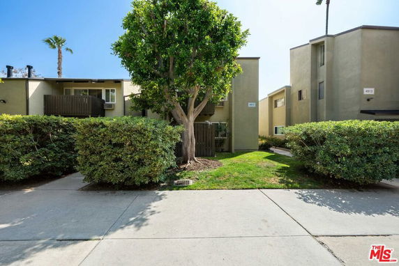 Front view of a two-story apartment complex with balconies and a landscaped entrance.