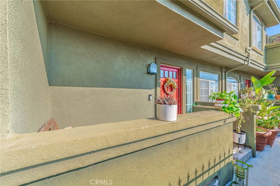 Front view of a residential building with a red door and plants.