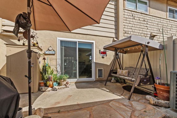 Outdoor patio area with a swing, potted plants, and a sliding glass door.