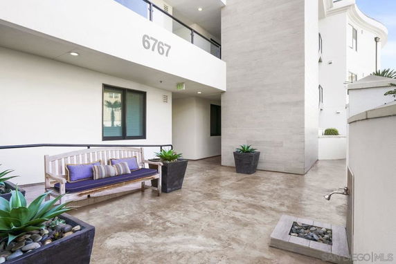 Exterior view of a building with a bench and potted plants in an open area.