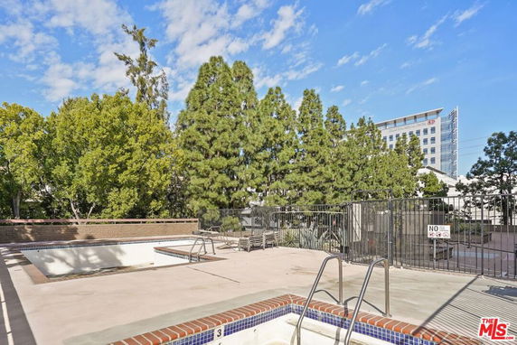 Outdoor swimming pool area with surrounding trees and a view of a building.
