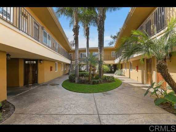 Central courtyard of a two-story apartment complex with surrounding walkways and palm trees.