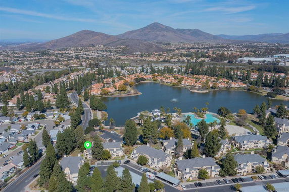 Aerial view of residential area with a large lake and distant mountains.