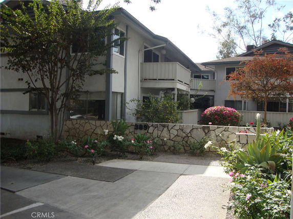 Front view of a two-story building with balcony and stone exterior wall.